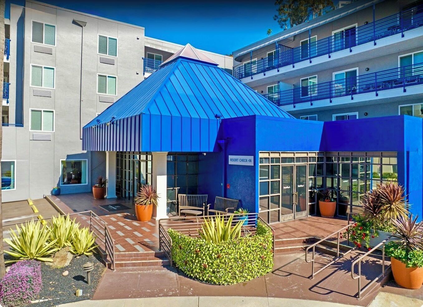Un edificio moderno con techo azul, una recepción y plantas en macetas.