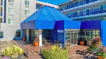 A modern building with a blue roof, a check-in desk, and potted plants.