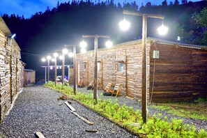 A row of log cabins with a gravel path and small plants in front.