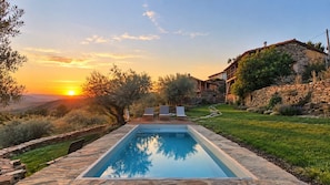 A rectangular pool with a stone border, surrounded by a grassy area and a stone wall.
