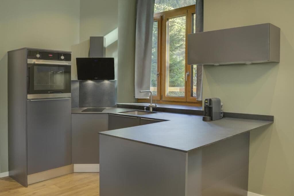 Una cocina moderna con horno integrado, televisor de pantalla plana y cafetera.