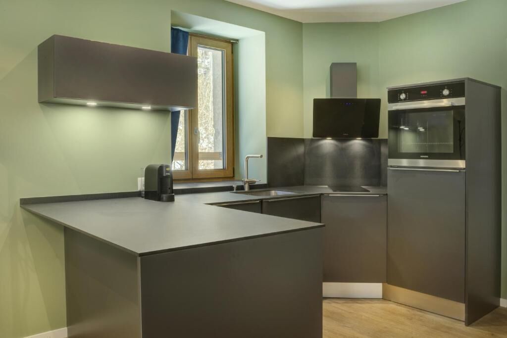 Une cuisine moderne dotée d’un îlot central intégré, d’un four à micro-ondes et d’un réfrigérateur.