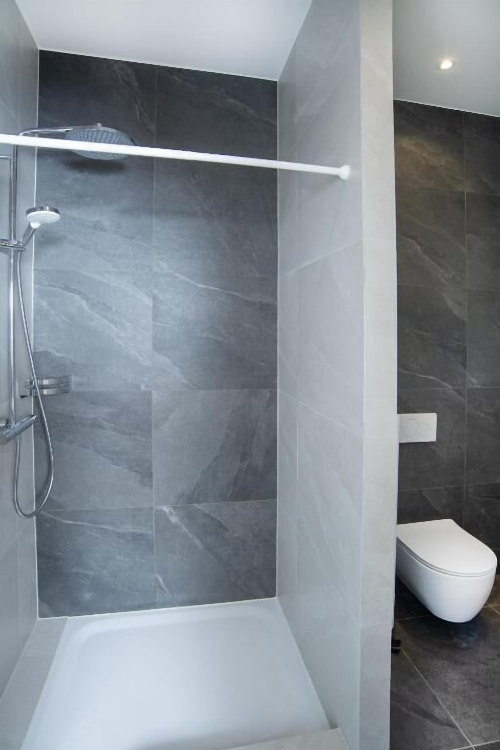 Une salle de bain moderne équipée d’une douche, de toilettes et d’une baignoire.