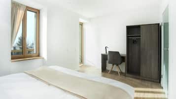 Een moderne slaapkamer met een groot bed, een bureau en een kledingkast.