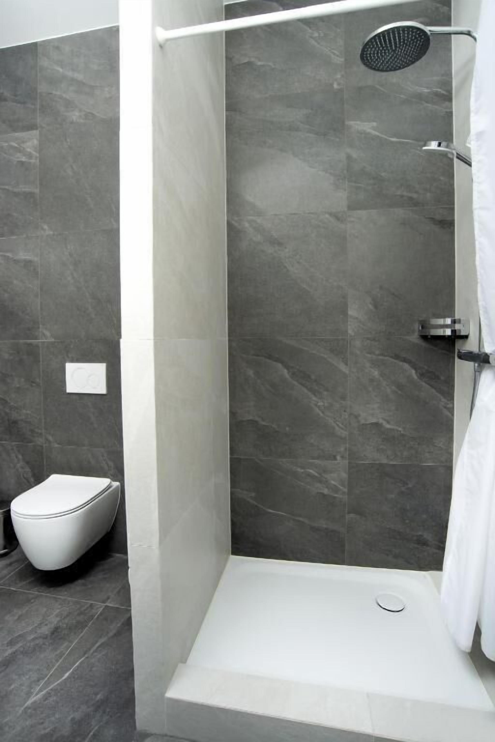 Un baño moderno con ducha, inodoro y lavamanos blanco.
