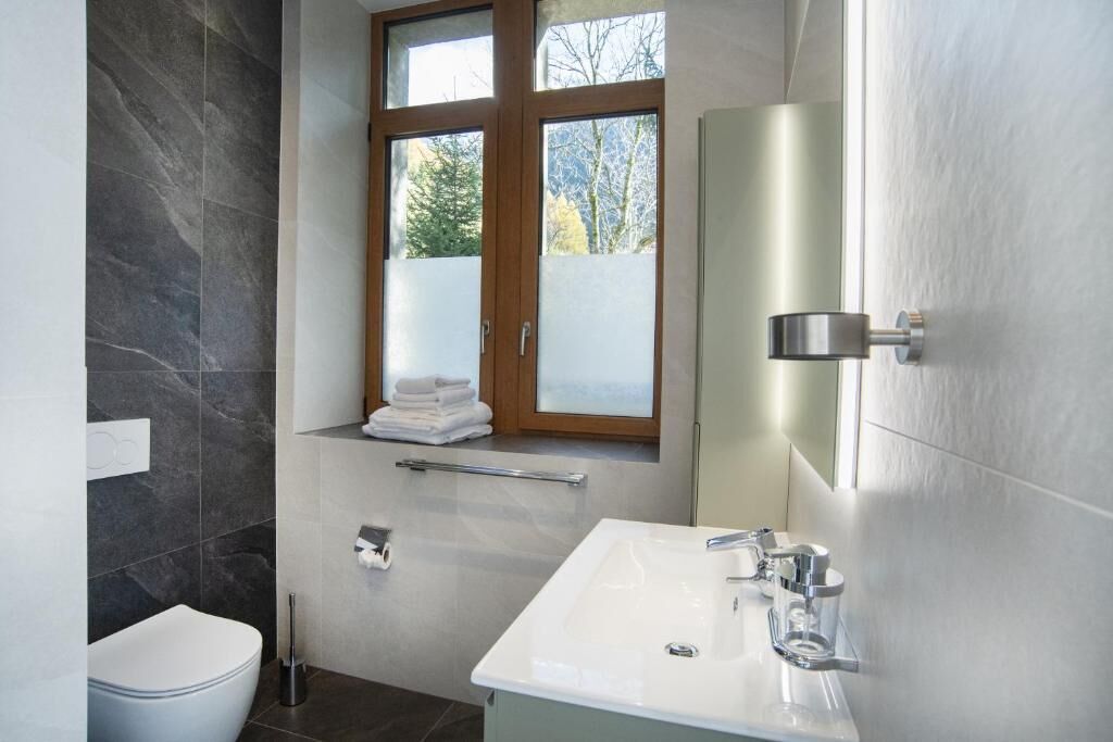 Un baño moderno con inodoro, lavamanos y ventana.