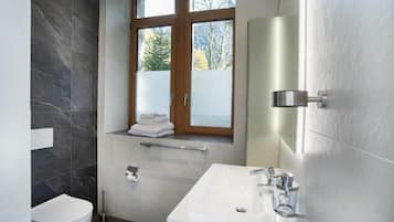Un baño moderno con inodoro, lavamanos y ventana.