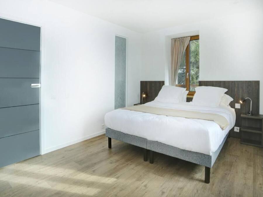 Een slaapkamer met een bed, nachtkastjes, een kledingkast en een raam met gordijnen.