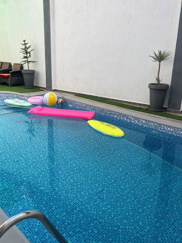 A swimming pool with a tiled floor and a few floating objects.
