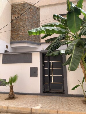 A building with a black door, a small window, and a stone wall.