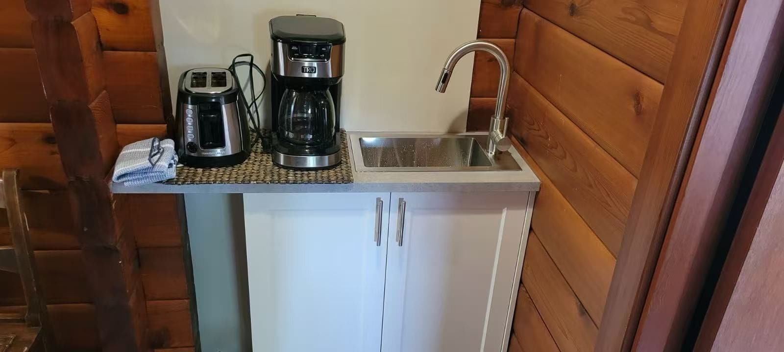 Une petite cuisine équipée d’une machine à café, d’un grille-pain et d’un évier.