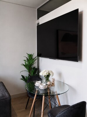 Ein modernes Zimmer mit einem Glastisch, einem schwarzen Stuhl, einer Topfpflanze und einer Blumenvase.