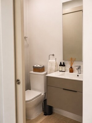 Ein Badezimmer mit Toilette, Waschbecken, Spiegel und Mülleimer.