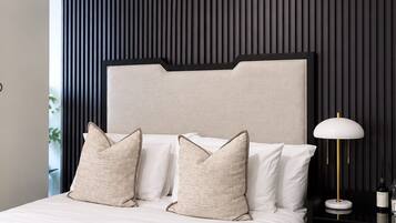 A modern bedroom with a large bed, a headboard, and a bedside table with a lamp.