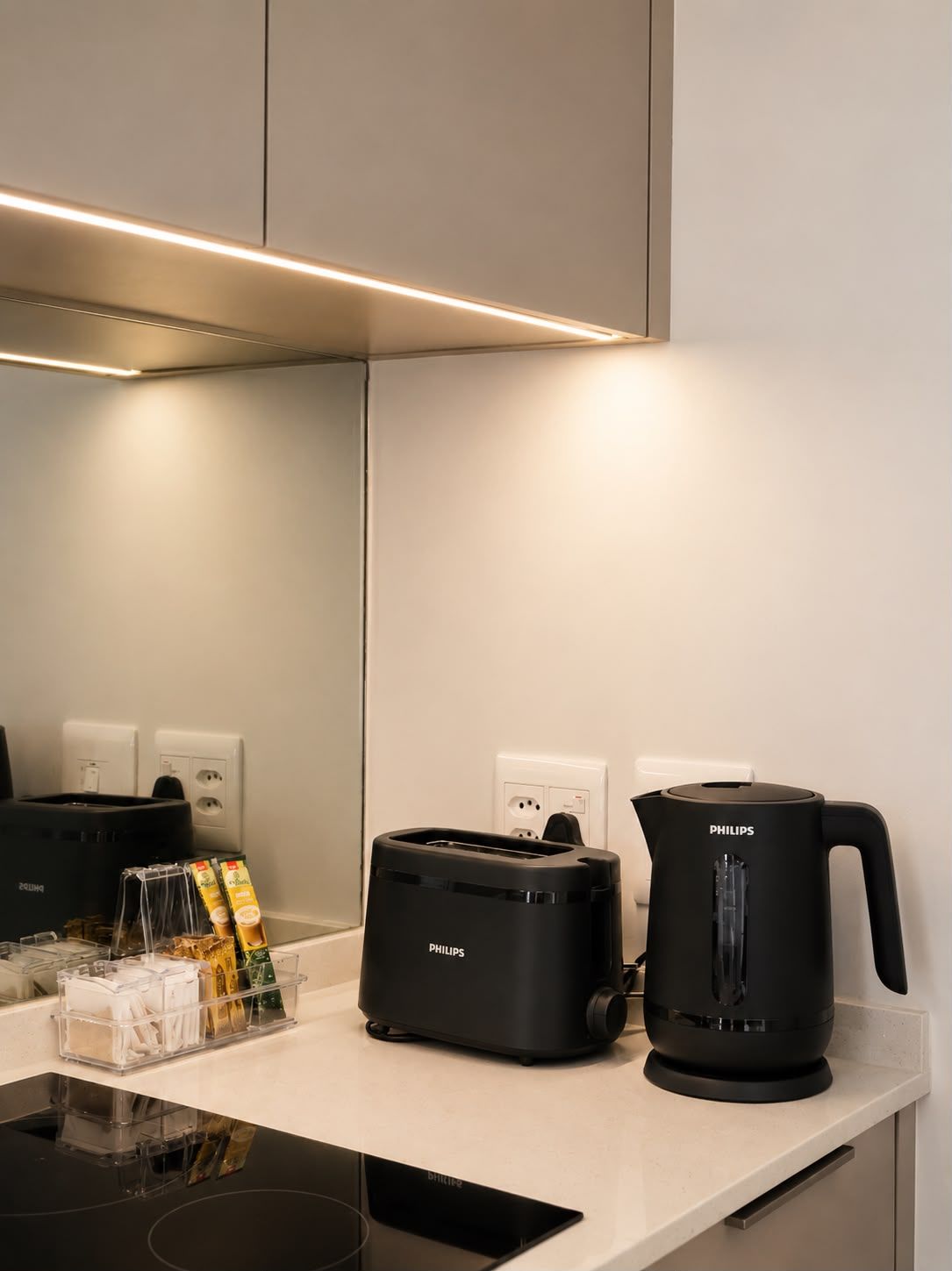 Eine moderne Küche mit einem schwarzen Toaster, einer schwarzen Kaffeemaschine und einem transparenten Aufbewahrungsbehälter mit Gegenständen auf der Arbeitsfläche.