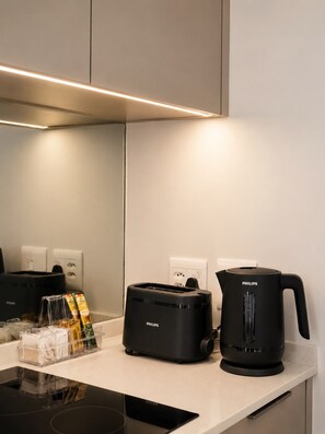 A modern kitchen with a black toaster, a black coffee maker, and a clear storage container with items on the counter.