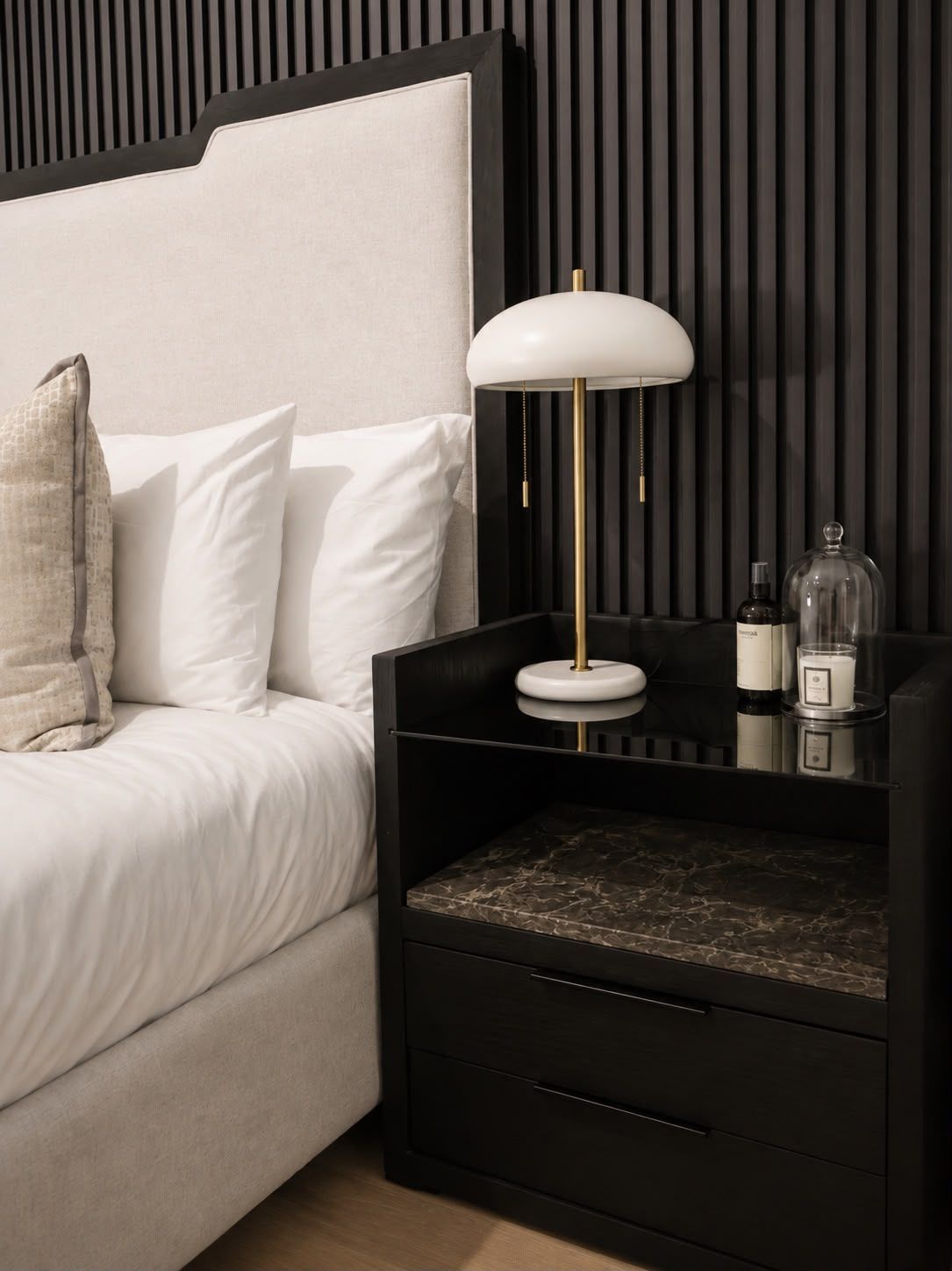 A modern bedroom with a bed, bedside table, lamp, and storage drawers.