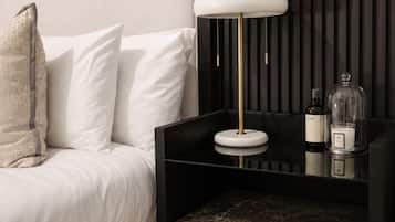 A modern bedroom with a bed, bedside table, lamp, and storage drawers.