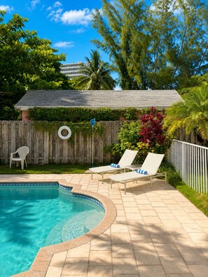 A backyard with a swimming pool, two lounge chairs, a wooden fence, and a tire swing. - BEACHaus Cottage -Pool- 2 Blocks from Beach+Pier (Deerfield Beach)