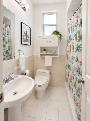 A bathroom with a sink, toilet, and shower curtain. - BEACHaus Cottage -Pool- 2 Blocks from Beach+Pier (Deerfield Beach)