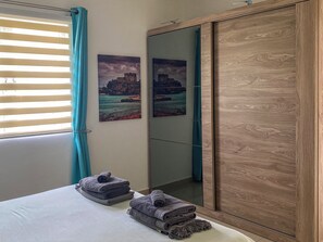 Ein Schlafzimmer mit einem Bett, zwei an der Wand befestigten Bildern, einem Spiegel und einem Holzschrank.