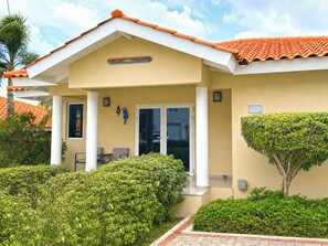 A building with a tiled roof, a covered entrance, and a security sign. - Villa Paradise Cove – Your Gateway to Paradise (Jan Thiel)