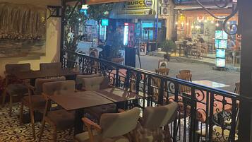 Un comedor interior con mesas y sillas, vista a la calle y un letrero de restaurante.