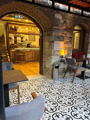 An interior with a café area, a stone wall, and patterned flooring.