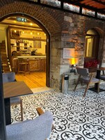 Un interior con una zona de café, una pared de piedra y suelo estampado.