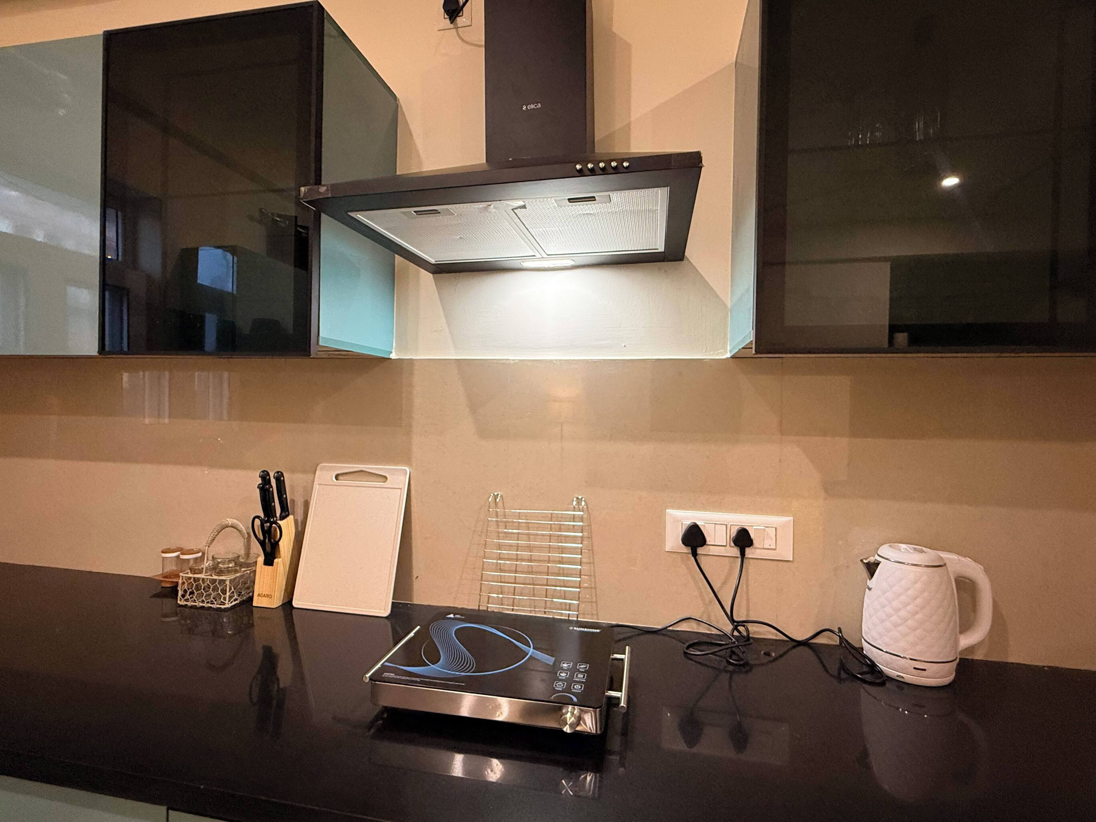 A modern kitchen with a built-in oven, a kettle, and a coffee maker on the counter.