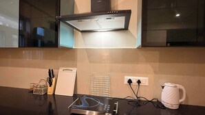 Una cocina moderna con horno empotrado, hervidor y cafetera sobre la encimera.