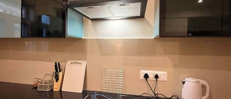 A modern kitchen with a built-in oven, a kettle, and a coffee maker on the counter.