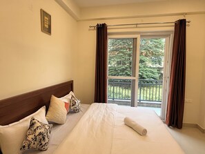 Ein Hotelzimmer mit einem Bett, einem Fenster mit Vorhängen und Blick auf Grünfläche.