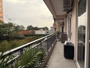 Un balcon donnant sur un quartier résidentiel, avec une poubelle et un pot de fleurs.