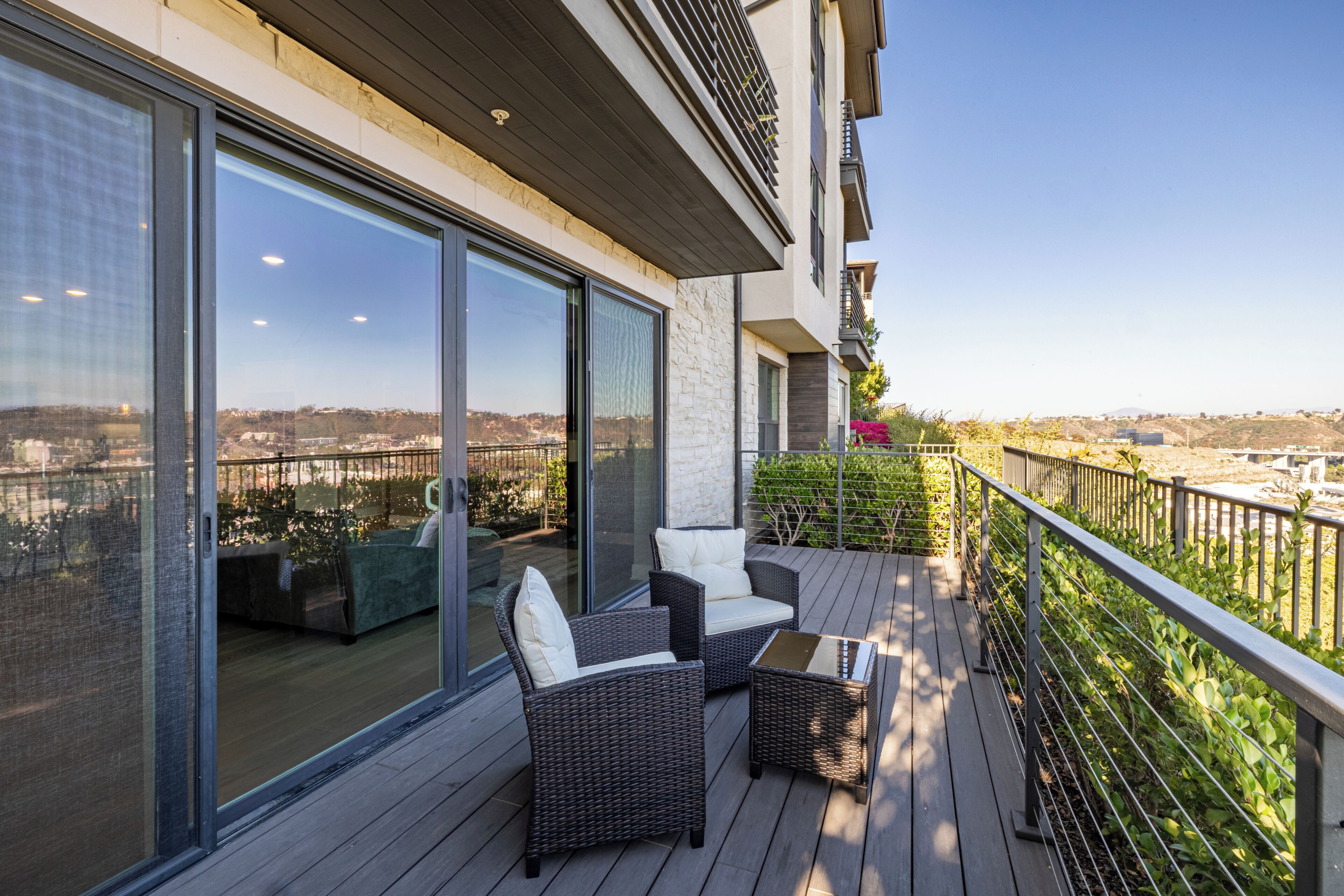 A balcony with wicker furniture and a view of a cityscape.