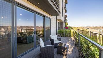 A balcony with wicker furniture and a view of a cityscape.