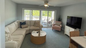 Un salon comprenant un canapé, une table basse, un téléviseur et un ventilateur de plafond.