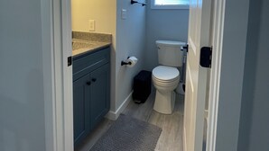 Une petite salle de bain comprenant des toilettes, un lavabo et une fenêtre.