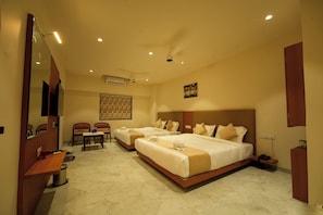 A hotel room with two beds, a desk, chairs, a mirror, and a ceiling fan.