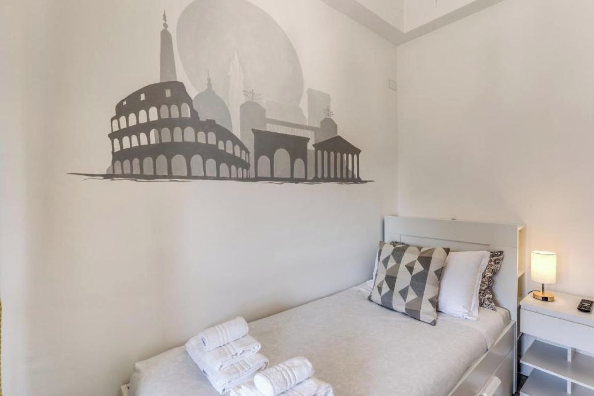 A hotel room with a bed, a nightstand, and a wall decoration of a cityscape.