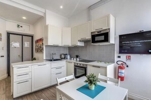 A modern kitchen with white cabinetry, a microwave, and a built-in oven. - Domus Heroas near Vatican (Rome)
