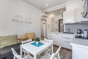 A compact kitchen with white cabinets, a dining table with chairs, and a small kitchenette. - Domus Heroas near Vatican (Rome)