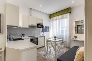 A compact kitchen with a dining area, a microwave, and a small table with chairs. - Domus Heroas near Vatican (Rome)