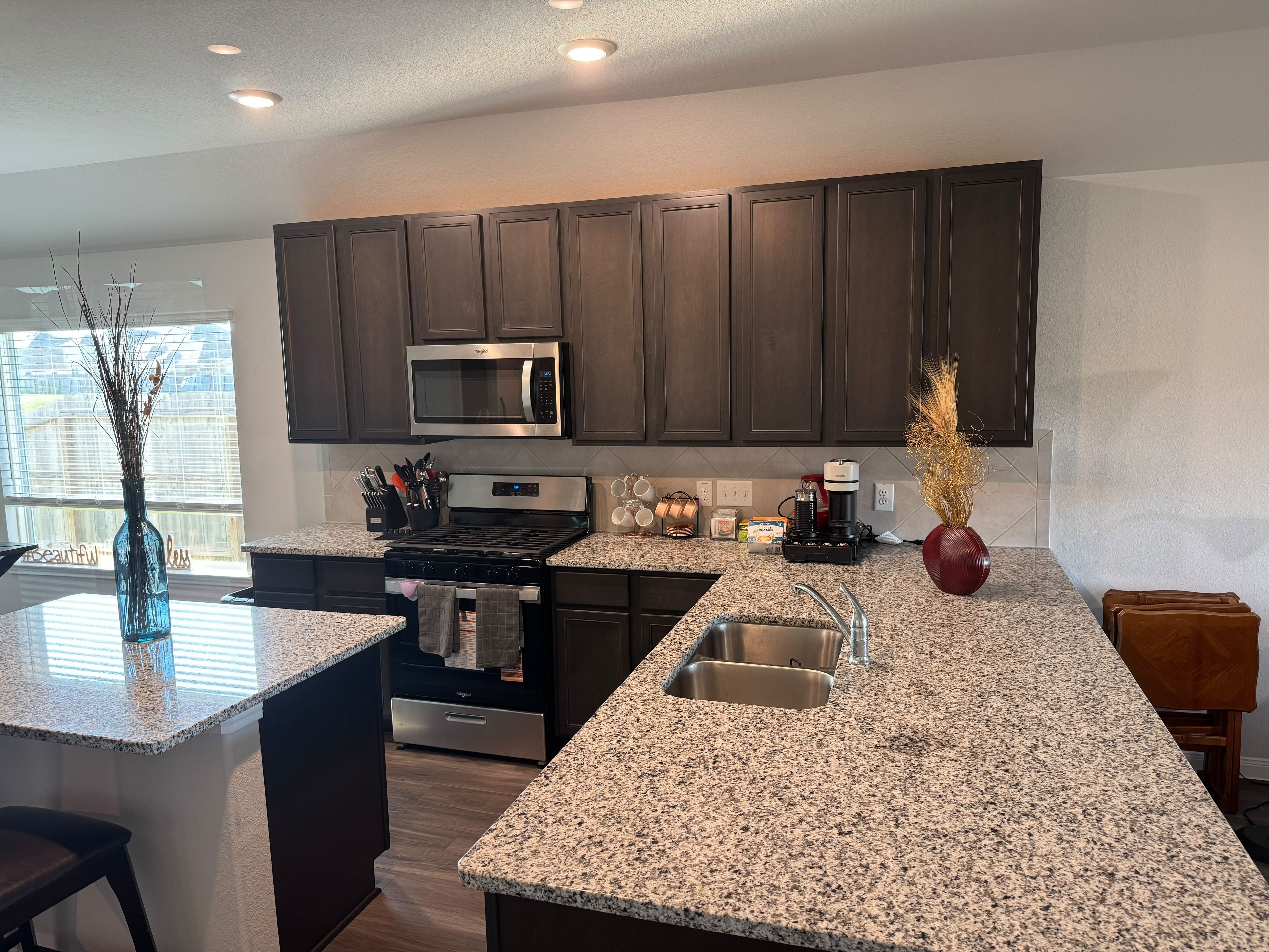 A modern kitchen with dark cabinets, a stainless steel microwave, a gas stove, and granite countertops.