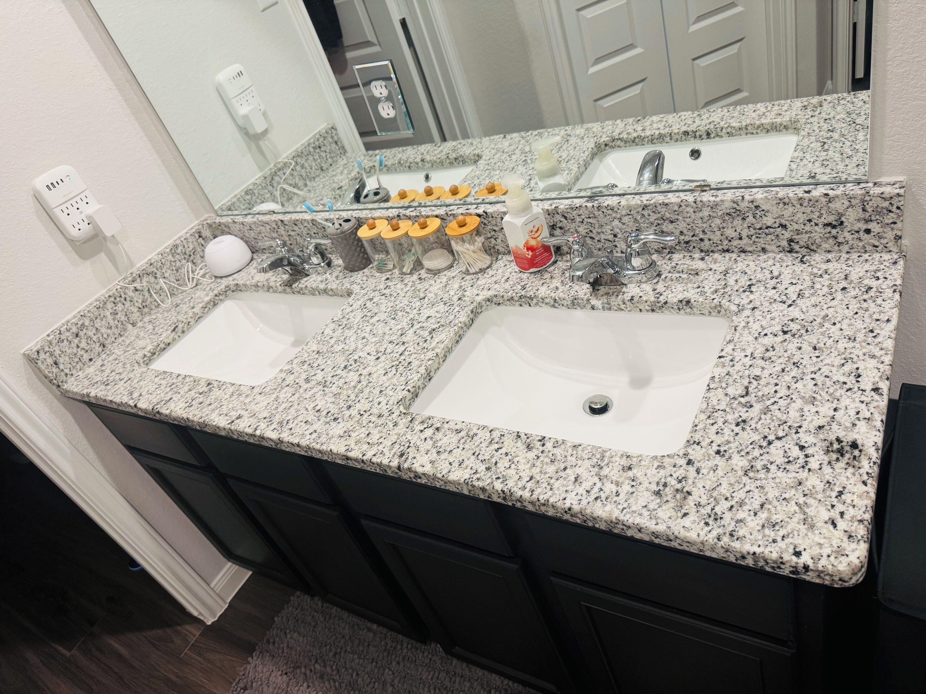A bathroom with two sinks, a mirror, and a countertop with various toiletries.