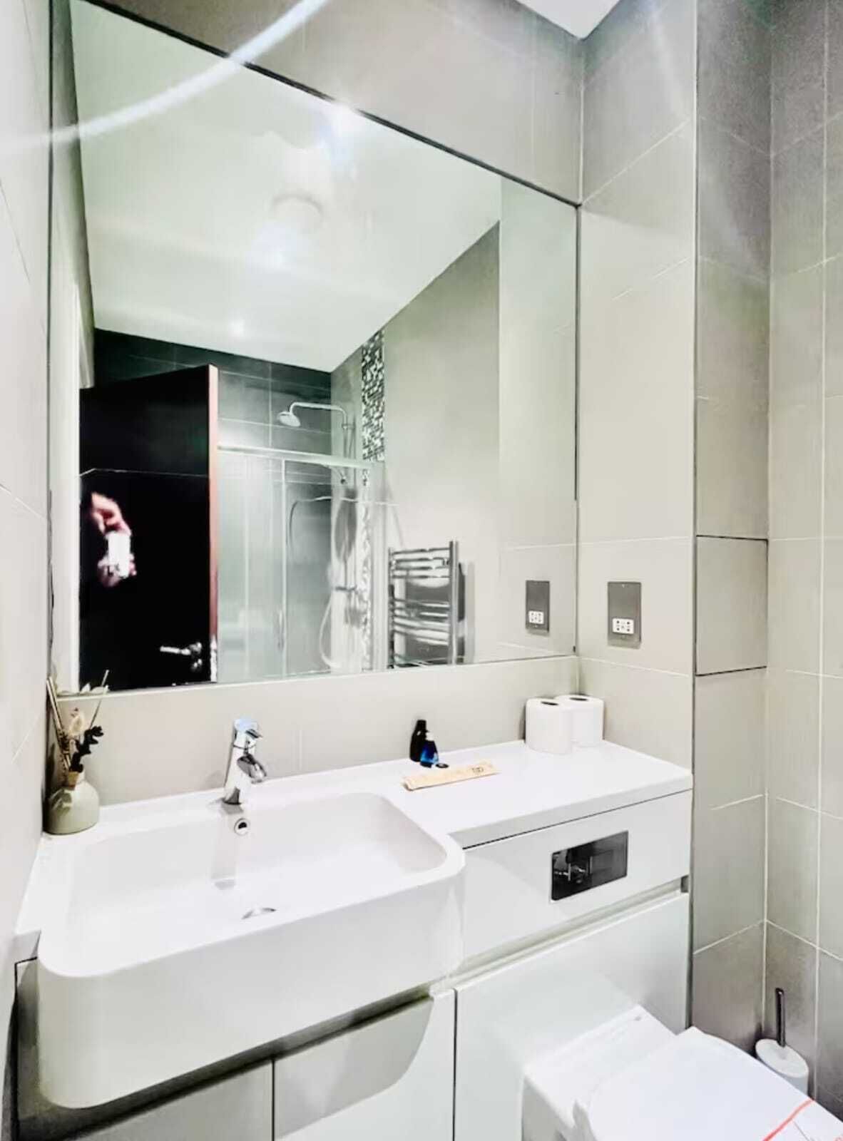 A modern bathroom with two sinks, a large mirror, and a towel rack.
