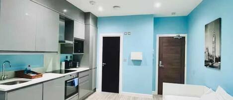 A modern hotel room with a kitchenette, a bed, and a bathroom.