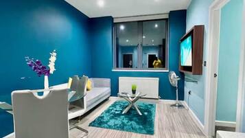 A modern living room with a grey sofa, a glass coffee table, and a blue accent wall.