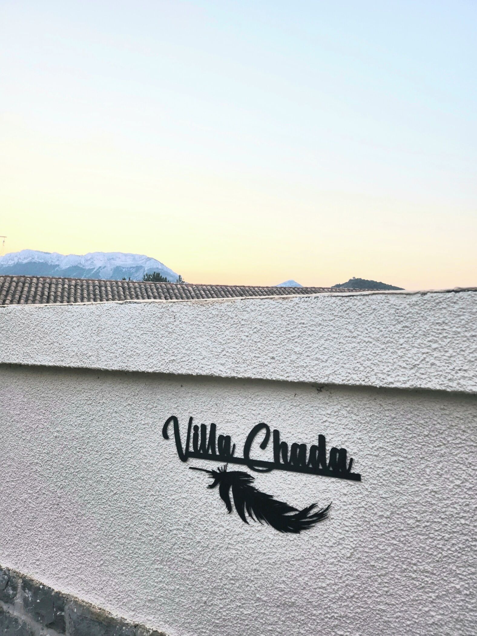 Een structuurwand met de tekst 'Villa Chada' en een palmboom in silhouet.