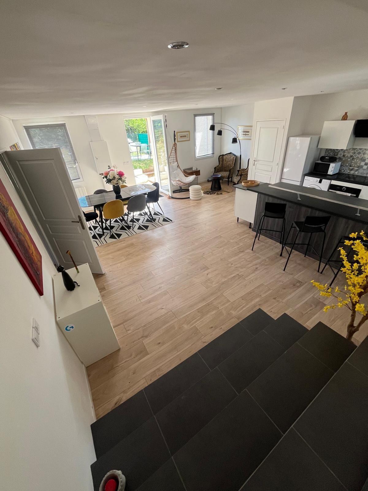 A modern kitchen with a dining area, wooden flooring, and a staircase leading to another level.
